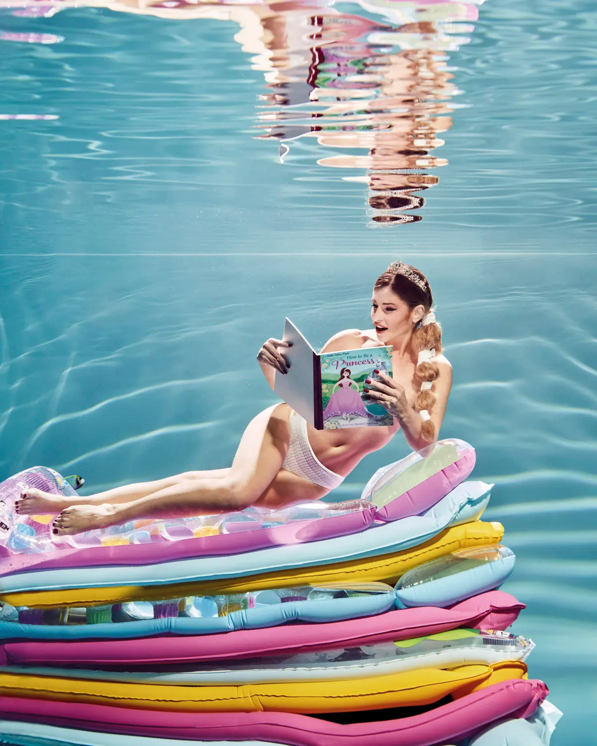 Une pinup lit un magasine sur un matelas gonflable